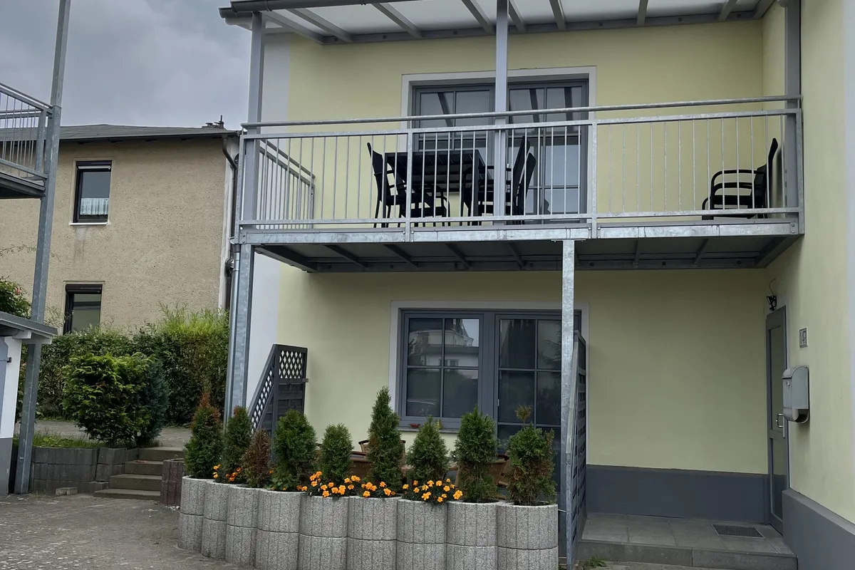 Hofseite mit Balkon und bepflanzter Terrasse